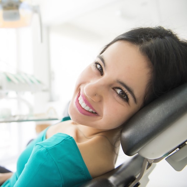 Young woman with dark hair in a green top looking back after a dental extraction